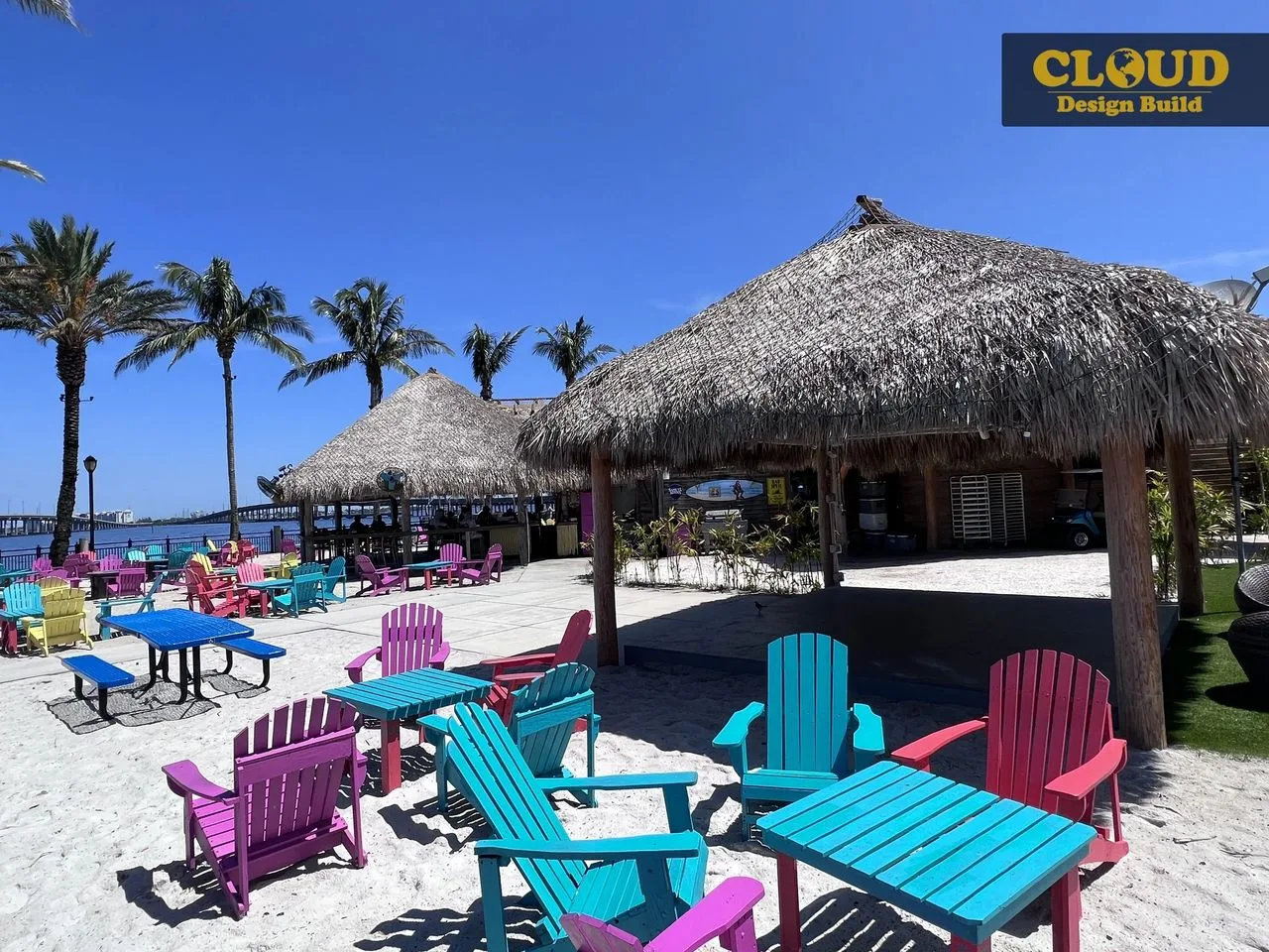 Colorful Adirondack chairs and thatched tiki huts on a Southwest Florida waterfront patio