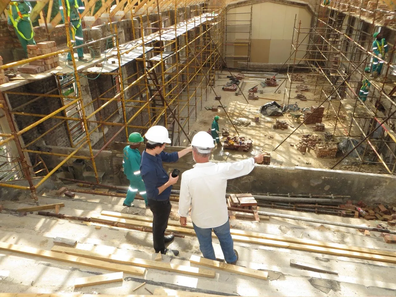 Two site inspectors looking down at brickwork from an elevated scaffold platform